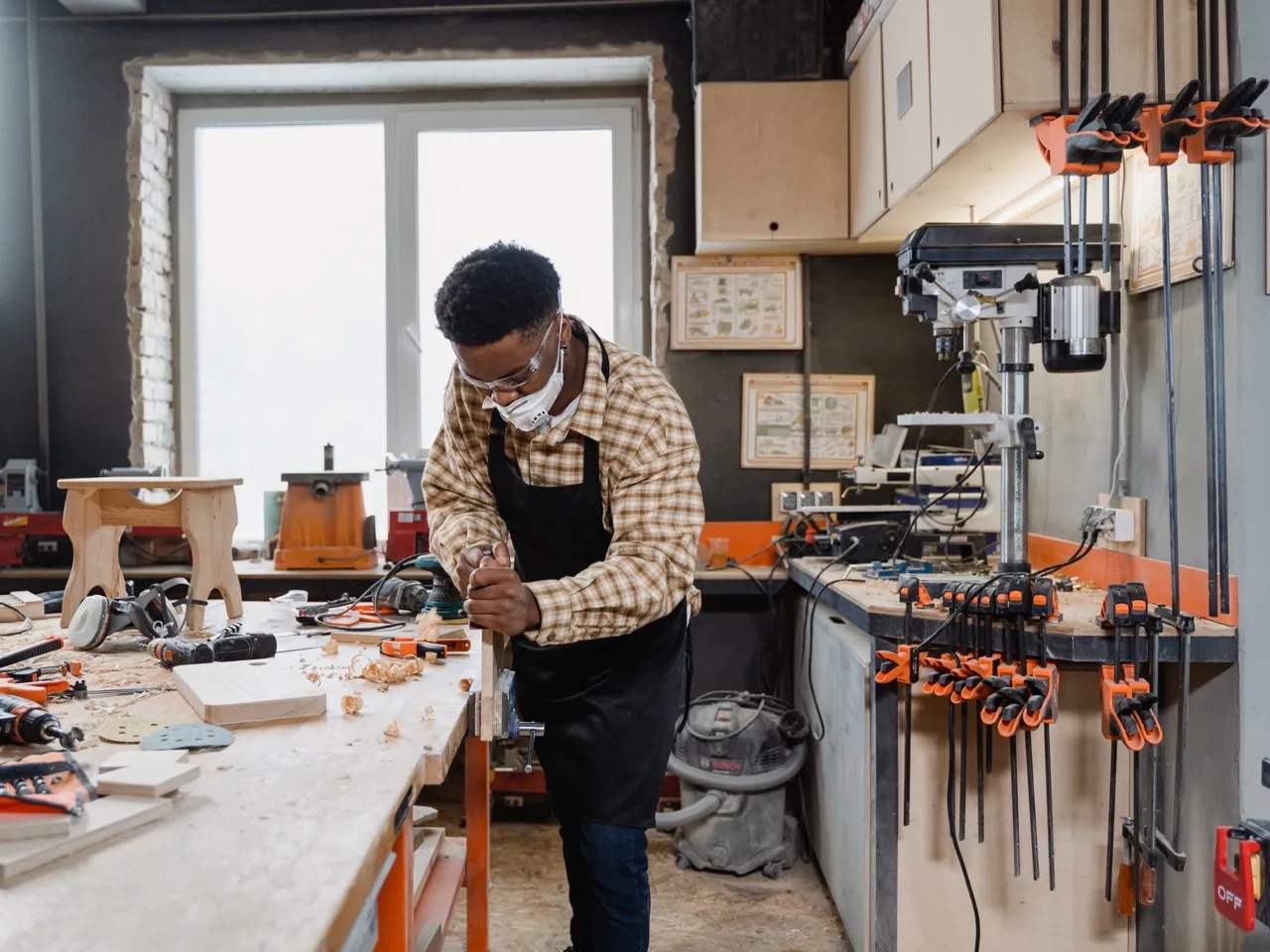 A man focused on crafting a woodworking project in his cozy workshop, surrounded by tools and wood pieces.